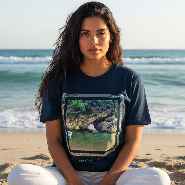 Model wearing Emerald Cove Photography Art Tee by Gena Sage Studios featuring framed coastal rock and emerald water photograph on navy shirt at the beach