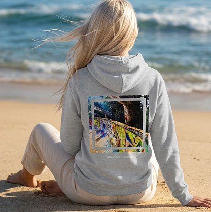 Person sitting on a beach wearing a hoodie with a colorful graphic on the back